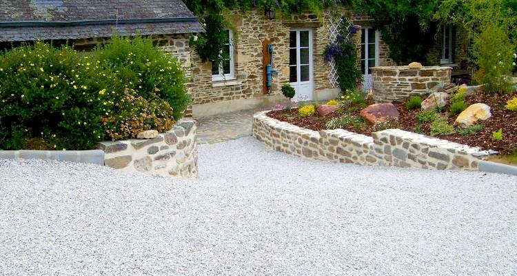 Light gravel driveway beside a stone cottage with stone wall edging